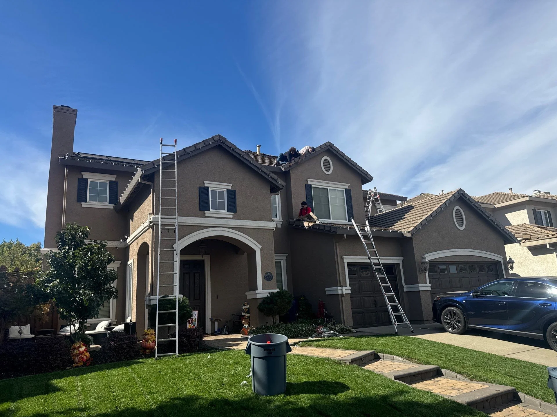 Santa's Lights crew installing Christmas lights along the tile roofline near solar panels in Rocklin