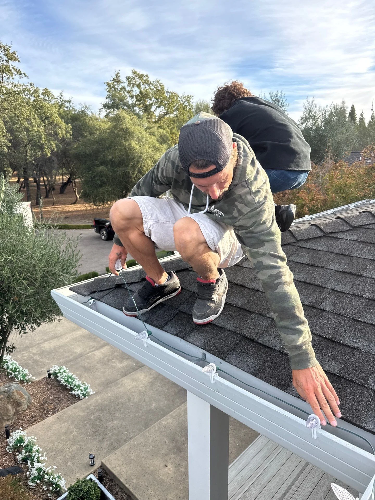 Two-person Santa's Lights crew installing Christmas lights together on a Loomis roofline