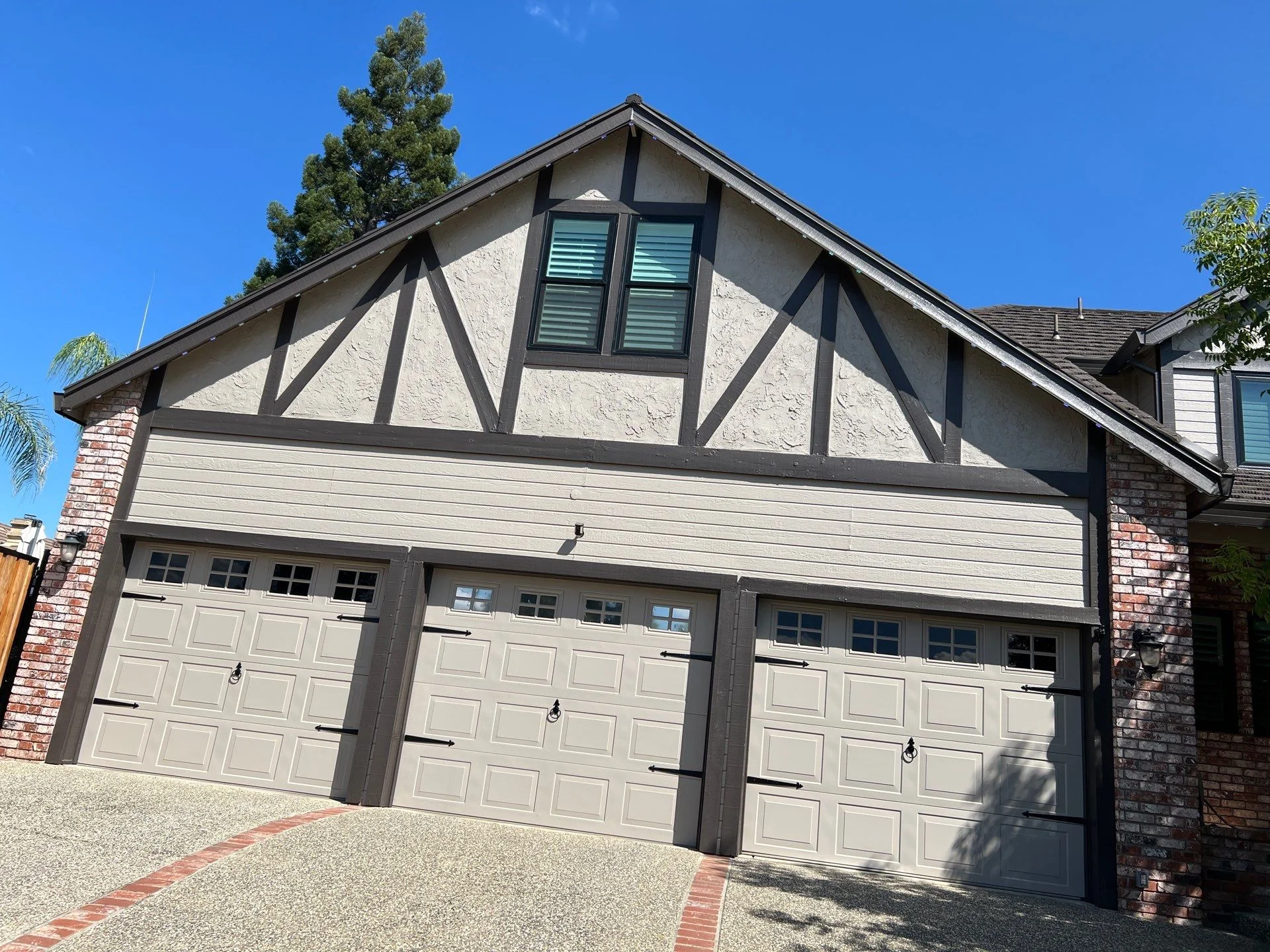 Tudor style home in Folsom, California with dark half timbering, brick columns, and a three car garage gable