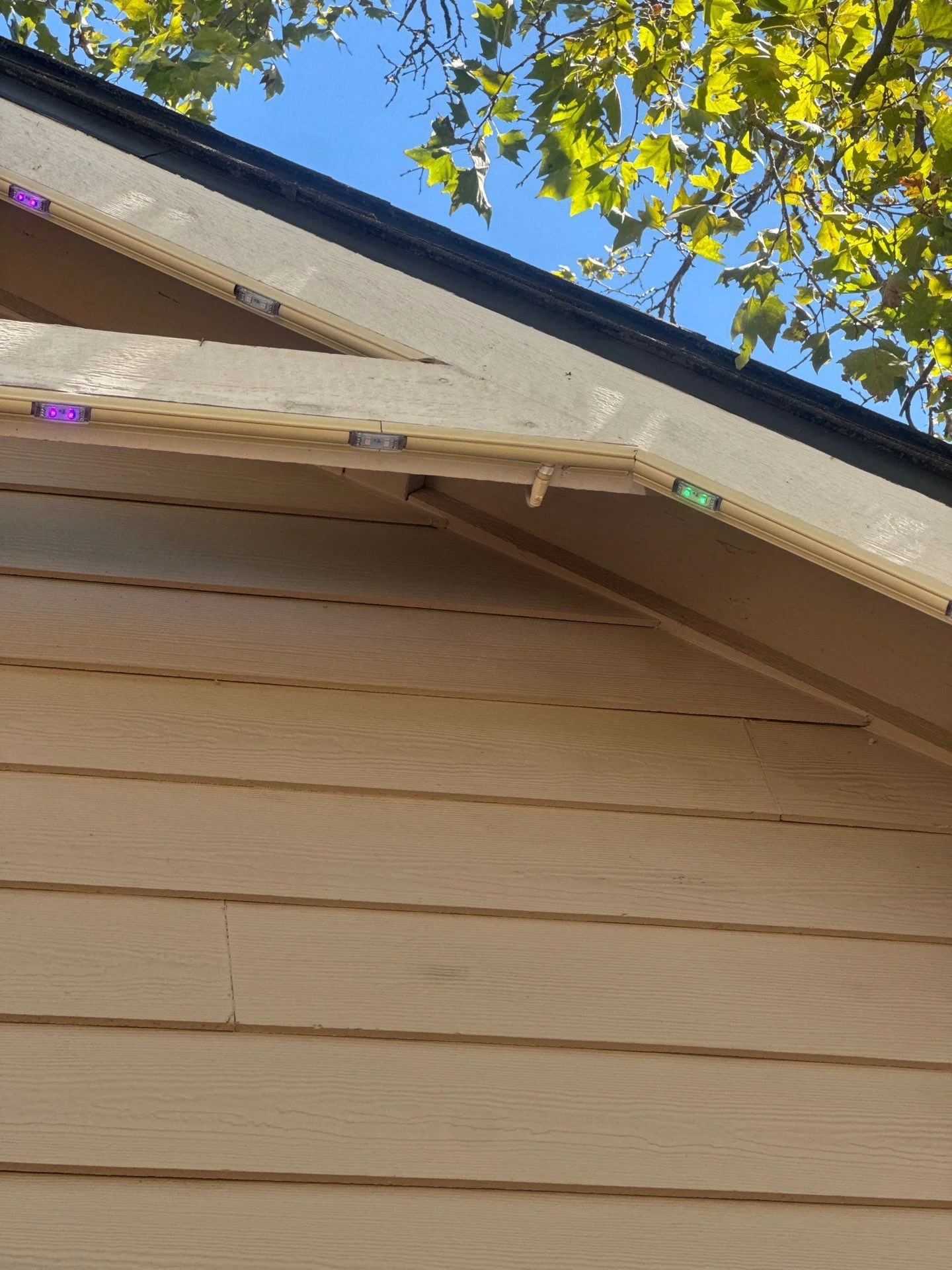 Close up of permanent lighting pebbles showing purple, green, and amber colors along a gable on an East Sacramento home