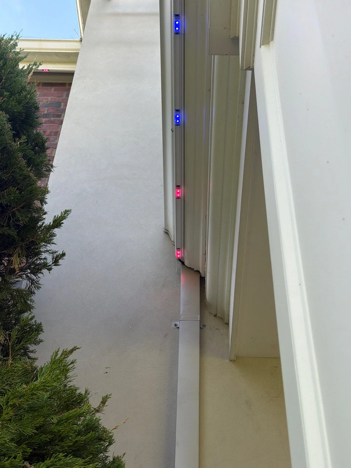 Permanent lighting track glowing blue and red during a color test on a stucco home
