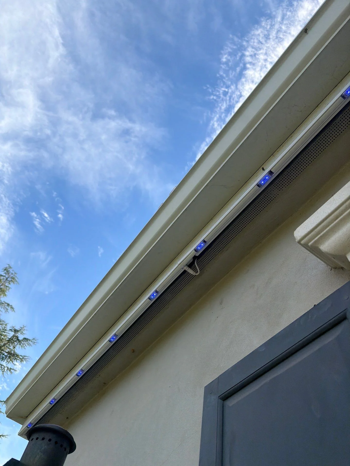 Permanent lighting track mounted along a gutter and soffit on a brick and stucco home